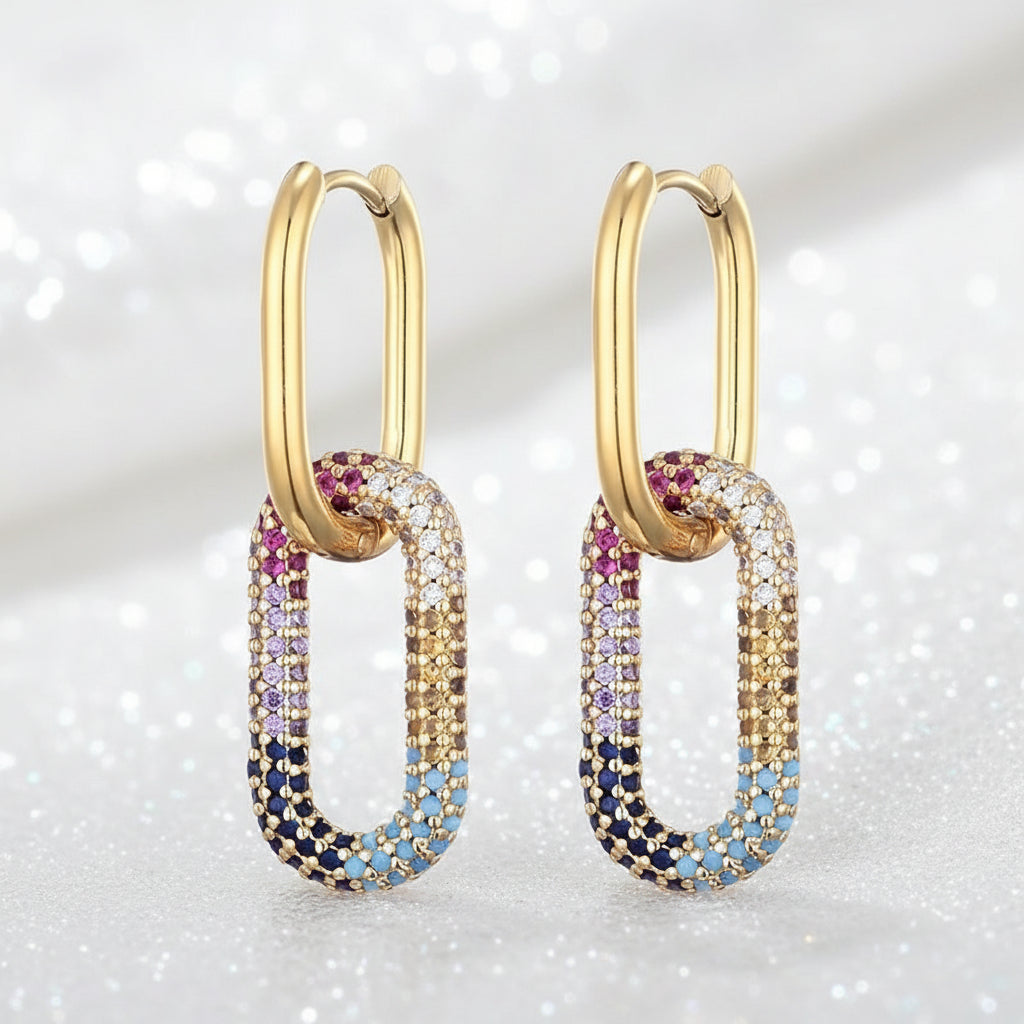 Gold hoop earrings with multicolored gemstones on a sparkling background