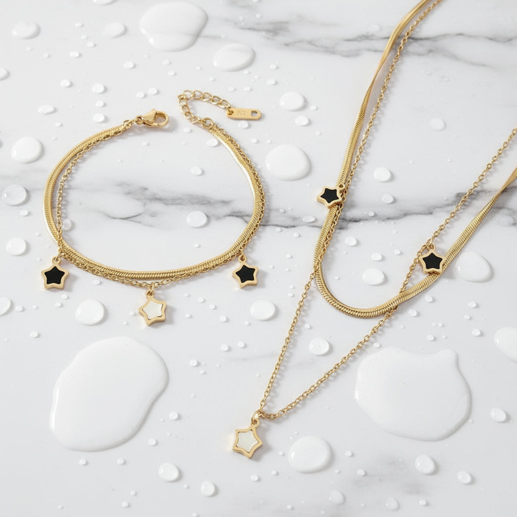 Gold bracelet and necklace set with star-shaped charms on a beige background